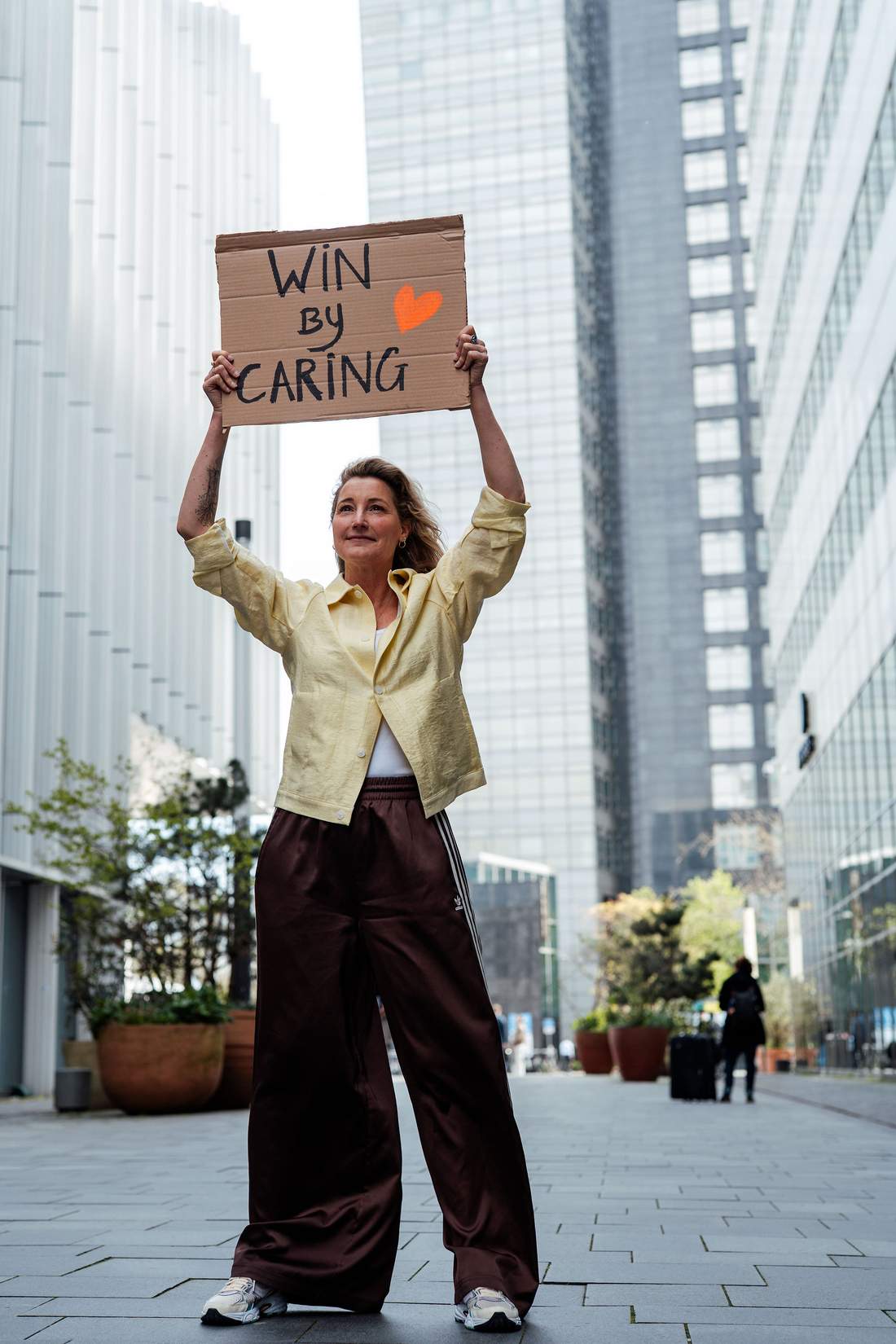 Dian houdt een bord omhoog met de woorden Win by caring