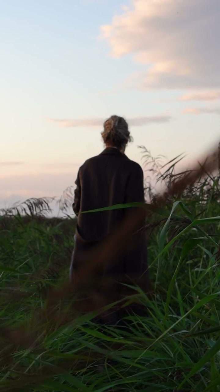 Dian staat rustig in het landschap terwijl het gras beweegt in de wind